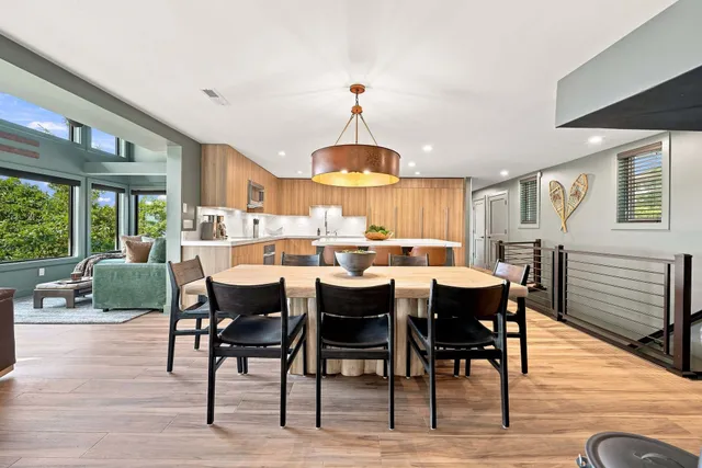 Dining table under a copper drum pendant, open to the kitchen and the view windows