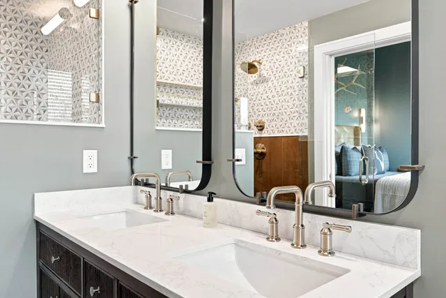 Double vanity with arched mirrors and patterned wallpaper
