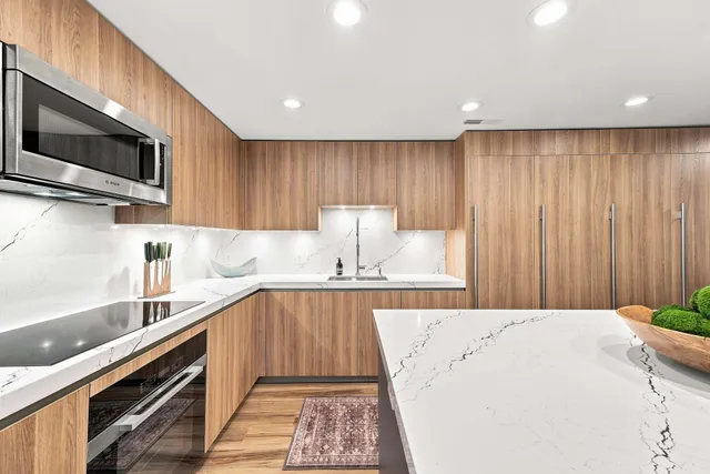 Kitchen with full height wood cabinetry and white veined stone counters