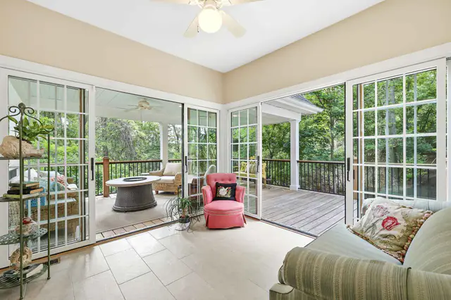 Interior photography  -  glass sunroom opening onto a covered deck with wooded views