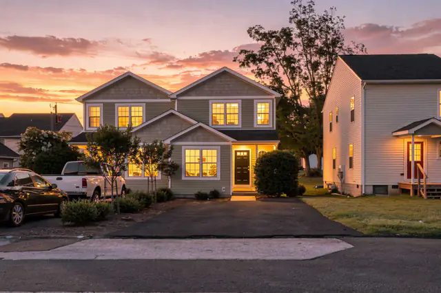 Twilight listing photo of a craftsman style home under a pink and orange sunset sky