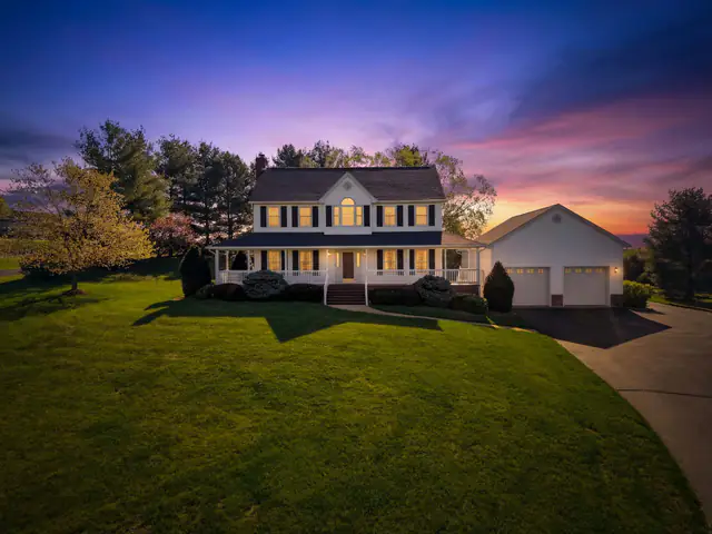 Twilight exterior photography  -  white colonial with wrap-around porch at sunset