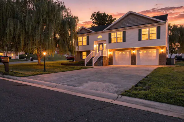Twilight real estate photo of a raised home framed by a willow tree, windows glowing at dusk, Shenandoah Valley VA